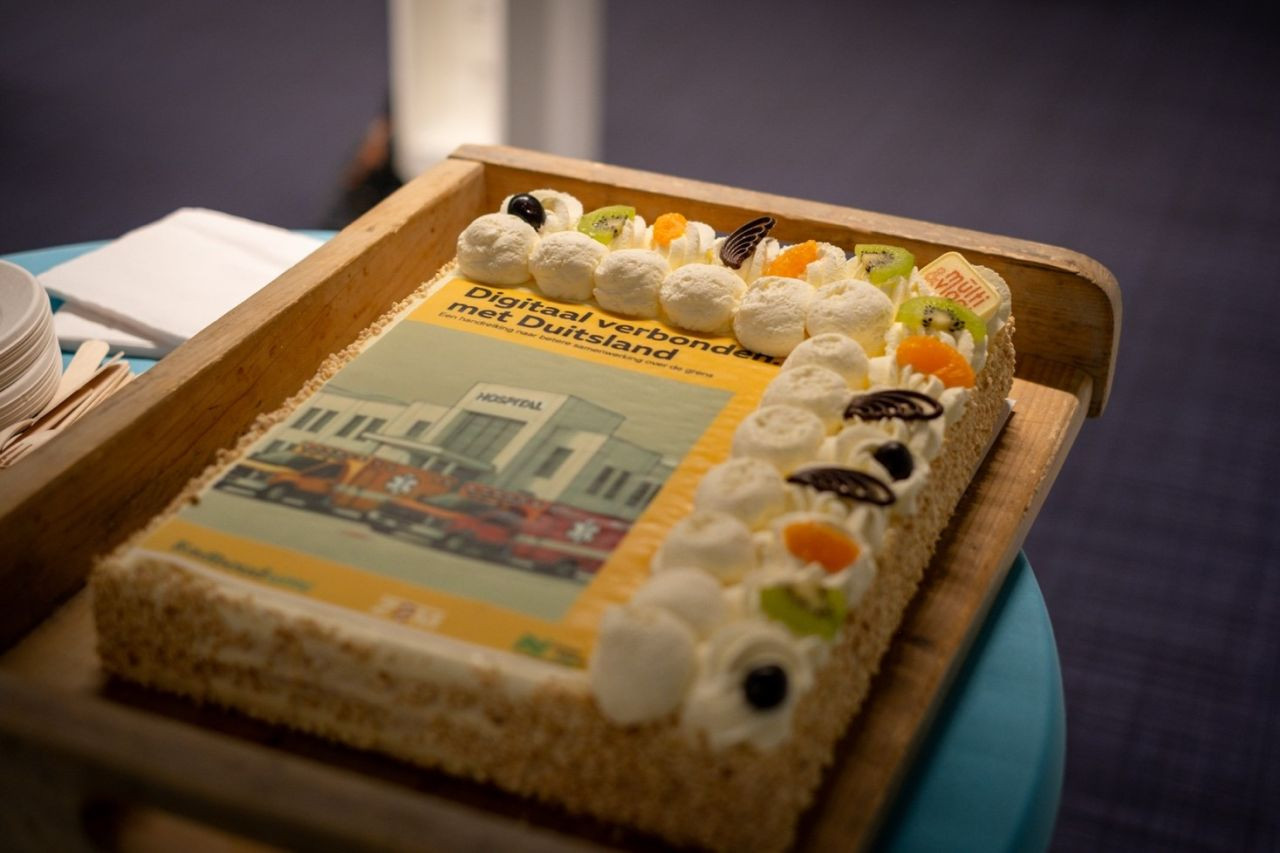Verzierte Sahnetorte mit Früchten und essbarem Deckblatt der Broschüre zur Anbindung an das NIDAklinik System